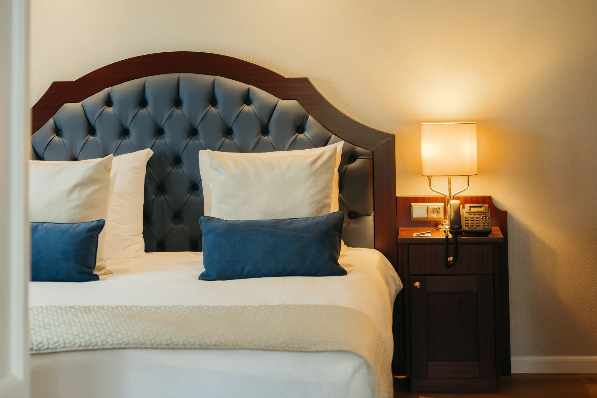 Luxe bed in MIVA-suite met blauwe kussens

